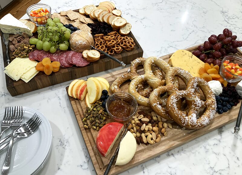 Long serving board with pretzels, fruit, cheese and dips at a party