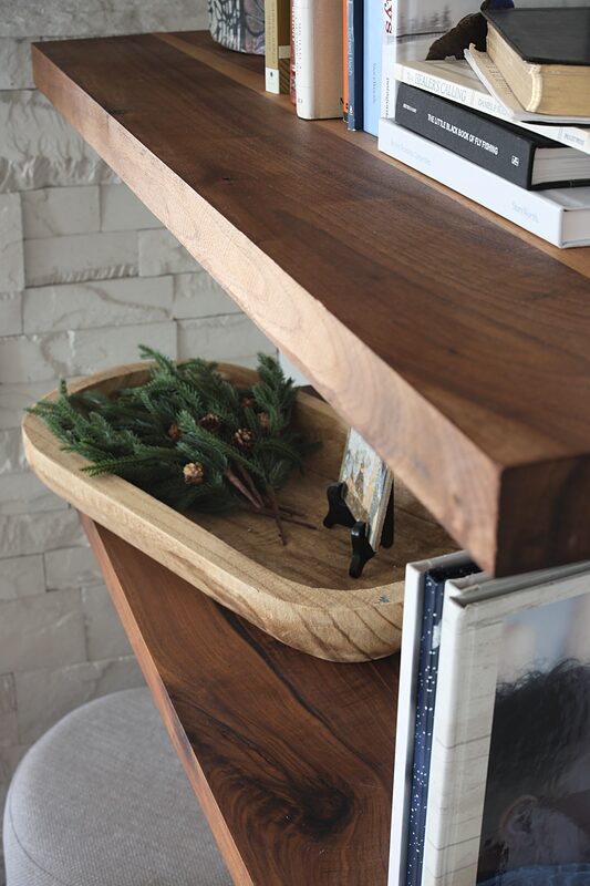 Close-up of a thick walnut floating shelf above a stone fireplace