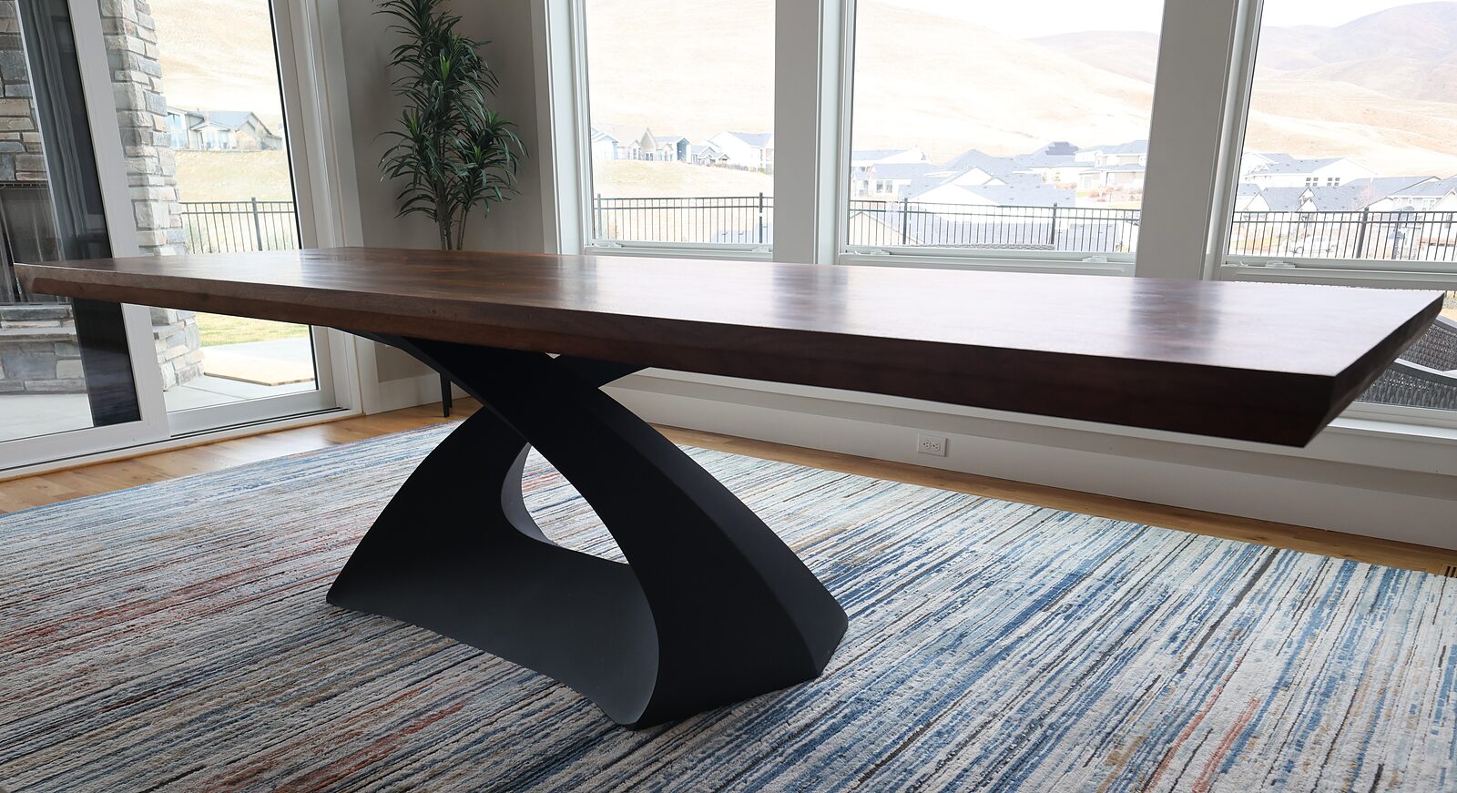 Side view of the ten-foot walnut table on its single sculpted steel base