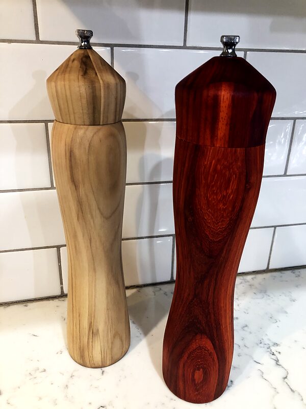 Pair of turned mills, one in light wood and one in deep red wood