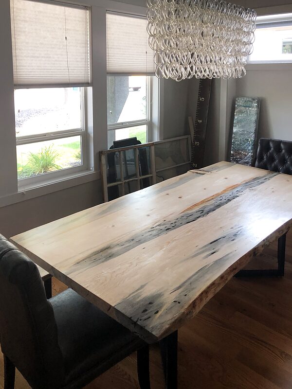 River table with a pale epoxy channel between two live-edge slabs, set in a dining room