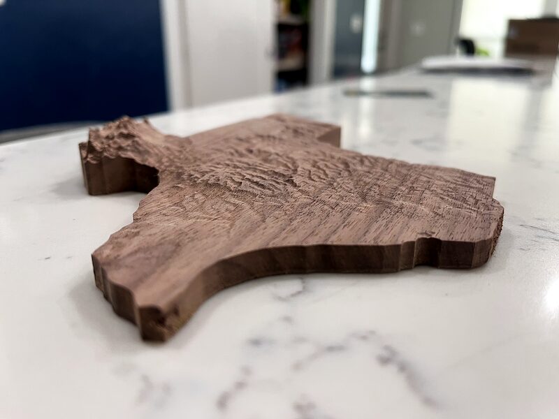Walnut topographic map of Texas carved from elevation data, on a marble counter